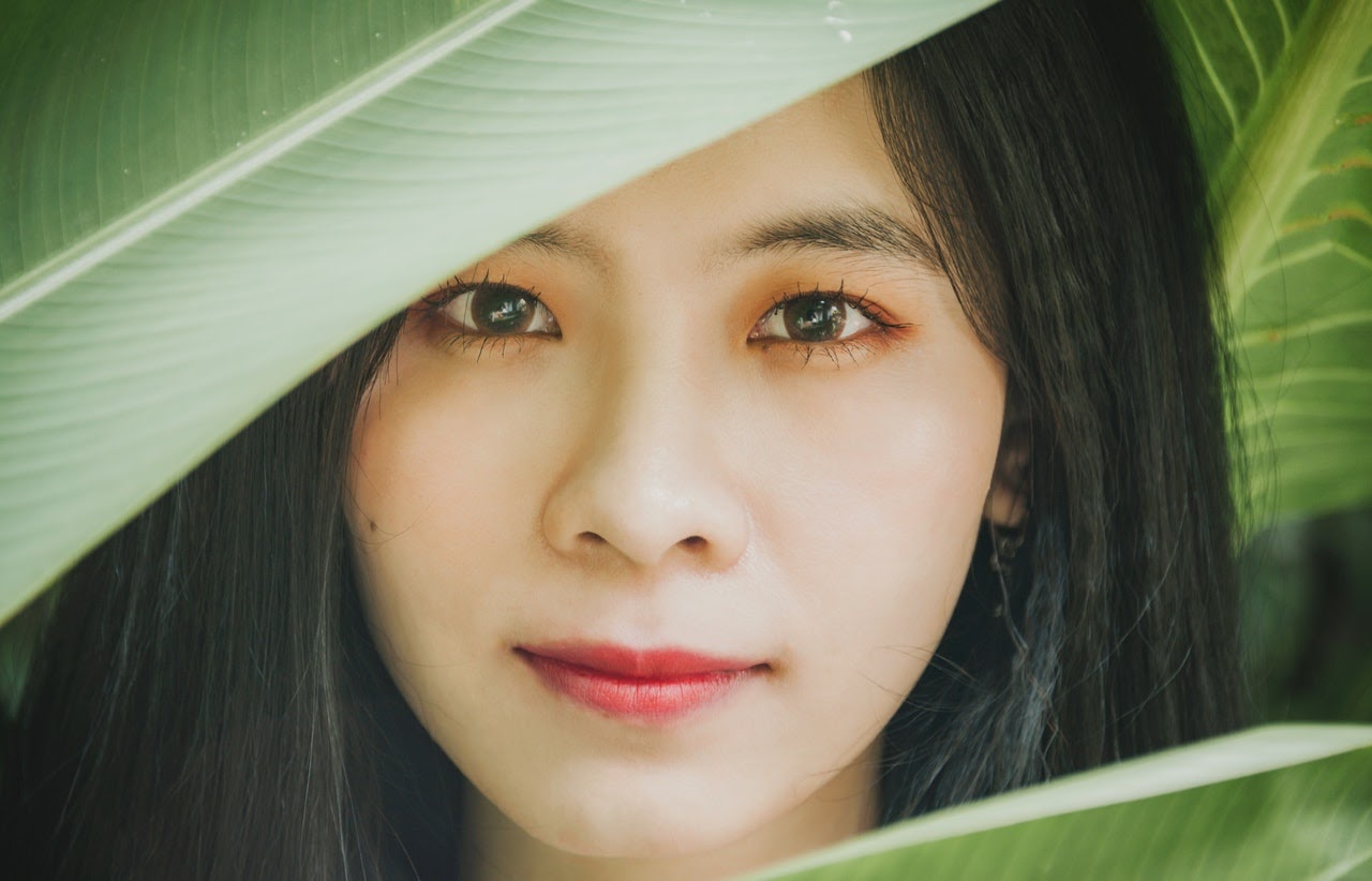 Philippine smiling woman standing beside leaf